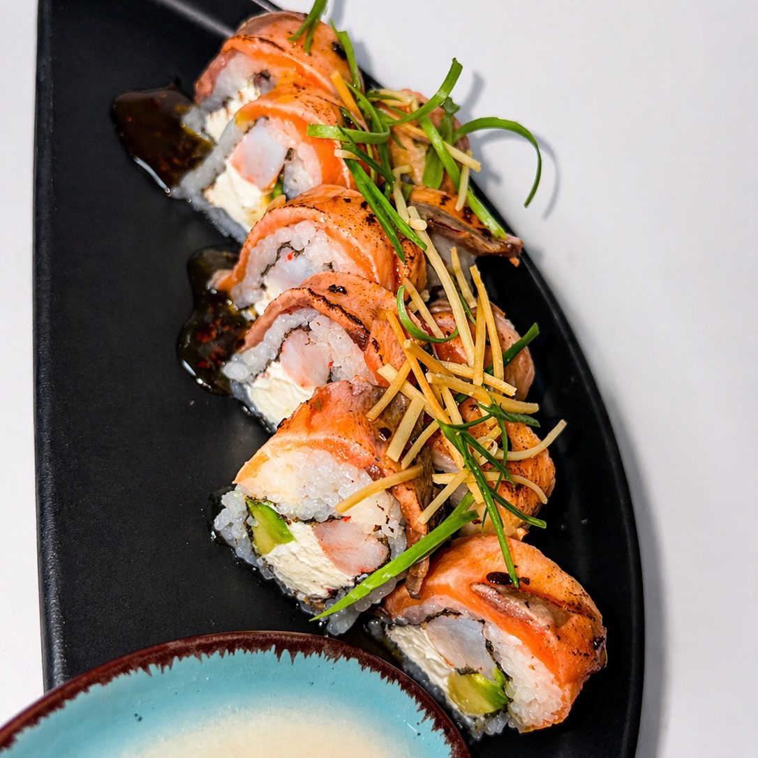 Rolls de salmón con camarón crispy y papas hilo sobre plato negro